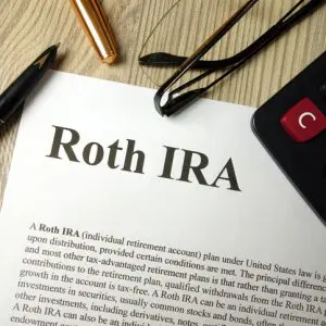 Roth IRA mockup with calculator pen and glasses