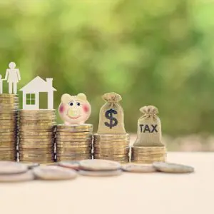 Estate Planning concept: family, home and money bags sitting on top of stacks of coins, financial